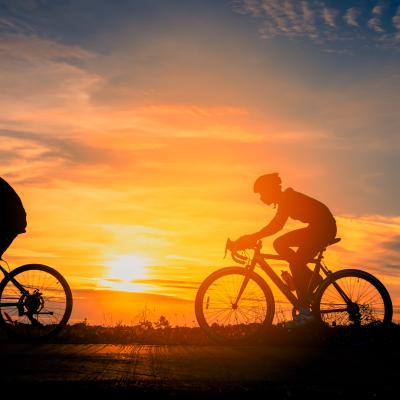 Photo of bicyclists silhouetted against a golden sunset