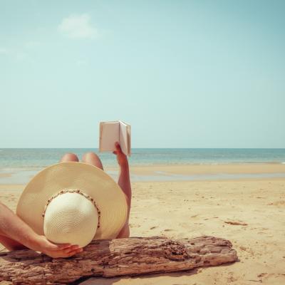 Person lying on the beach and reading a book