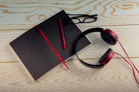 Book with headphones, glasses, and pen