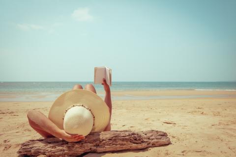 Person lying on the beach and reading a book