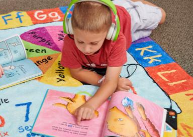 Child listening to a Wonderbook using headphones while reading along.